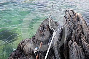 Spinning and landing net on a rocky shore