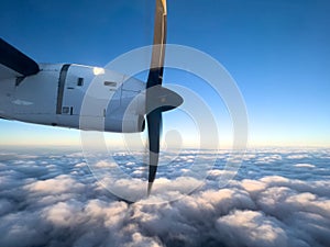 Spinning propeller of an airplane flying above the clouds in the blue sky