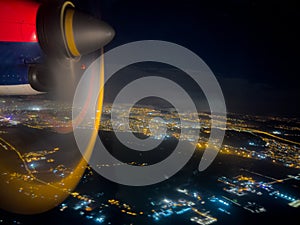 Spinning propeller of an airplane flying over a glowing city