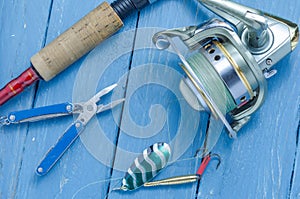 Spinning, reel, fishing green spoon and pliers. The bait and the tool of a fisherman.