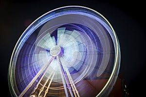 Spinning white purple ferris wheel in motion with black background