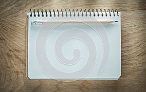 Spiral blank notepad pencil on wooden board