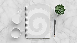 A spiral bound notebook with blank pages is centered on a marble surface