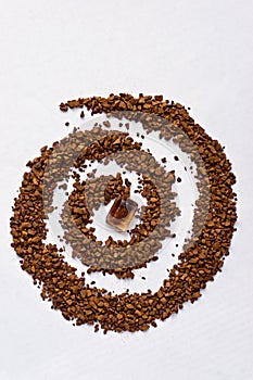 Spiral of coffee with a cane sugar cube on white