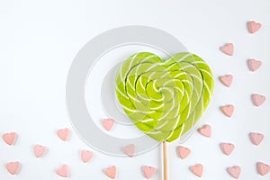 spiral heart lollipop on whitel background among small pink heart-shaped candies