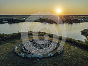 Spiral labyrinth made of stones on sunset lake