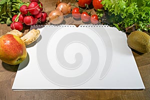 Spiral notebook with blank white paper and fresh food such as vegetables and fruits on a rustic wooden table, space for a