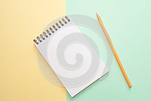 Spiral notebook with blank white sheet and colored pencil on multi-colored paper.
