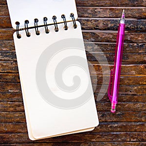 Spiral notepad blank page and pencil on wooden background. Empty sketchbook top view photo. White paper notepad