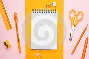 Spiral notepad with blank white sheet, orange scissors, ruler, pencil, sharpener pen on colorful backgrounds.