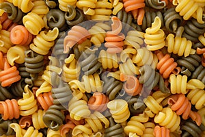 Spiral pasta background. Different colored pasta, top view.