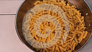 Spiral Pasta Falling into Metal Cooking Pan