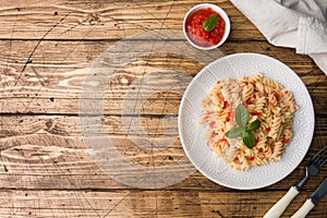 Spiral pasta mixed with cherry tomatoes and tomato sauce on a plate Copy space