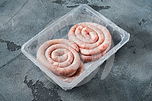 Spiral pork meat sausage  on gray background  in plastic pack   with space for text copyspace