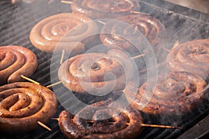 Spiral sausage coils, called srpska domaca kobasica, cooking on a serbian grill barbecue called rostilj. photo