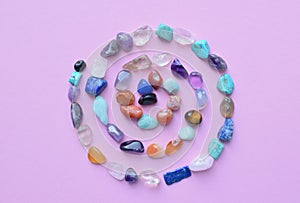 A spiral of semi-precious minerals on a pink background. Healing crystals