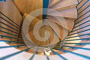 Spiral staircase, forged green handrail and wooden steps in modern home