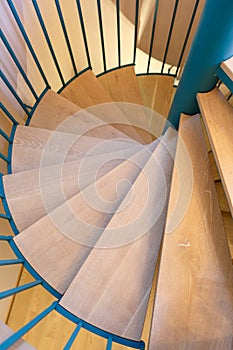 Spiral staircase, forged green handrail and wooden steps in modern home