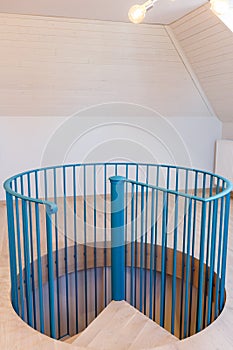 Spiral staircase, forged green handrail and wooden steps in modern home