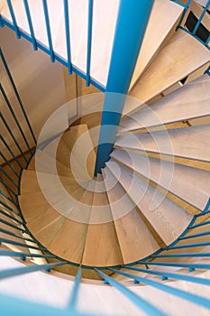 Spiral staircase, forged green handrail and wooden steps in modern home