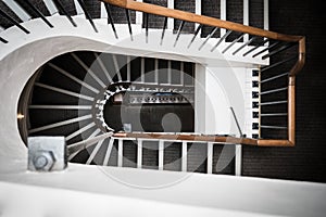 Spiral staircase in old Manor House three floors curving towards floor wooden banister and steel heating radiator