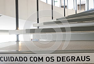 spiral stairs with the warning phrase written in Portuguese, "cuidado com os degraus".