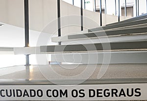 spiral stairs with the warning phrase written in Portuguese, "cuidado com os degraus". photo