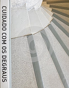 spiral stairs with the warning phrase written in Portuguese, "cuidado com os degraus". photo