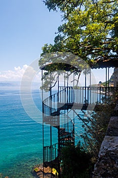 Spiraling staircase leading towards the vast ocean in Corfu, Greece