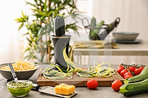 Spiralizer with zucchini noodles and vegetables on kitchen table