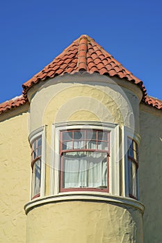 Spire or turrent on a house or building with red adobe roof tiles and beige stucco exterior with white accent paint