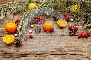 Spirit Christmas background. Fresh mandarins, dog-rose berries, candies, pine branches and cones, artificial snow