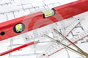 Spirit level and other measurement equipment lying on generic building plan