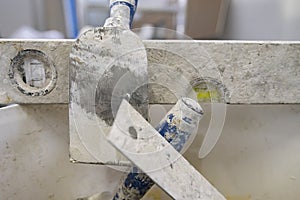 Spirit level with parts of other plastering tools on a metal plate under the plaster splashes