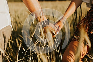 The spirit of travel, freedom and independence. Happy young couple in love running in the field in the sunset light. Messy hair. F