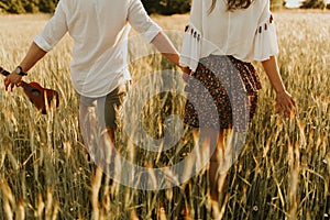 The spirit of travel, freedom and independence. Happy young couple in love running in the field in the sunset light. Messy hair. F