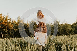 The spirit of travel, freedom and independence. Happy young couple in love running in the field in the sunset light. Messy hair. F