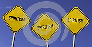 Spiritism - three yellow signs with blue sky background photo