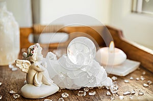 Spiritual angel message concept. Small cute angel figurine sit by crystal gemstone.