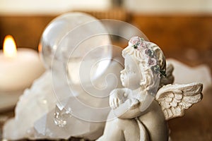 Spiritual angel message concept. Small cute angel figurine sit by crystal gemstone.