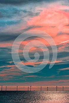 Spiritual awakening, Offshore wind farm cloudscape. Turbines under pink sunset sky