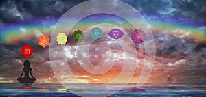 Spiritual background with chakras, human silhouette and rainbow in sea reflection