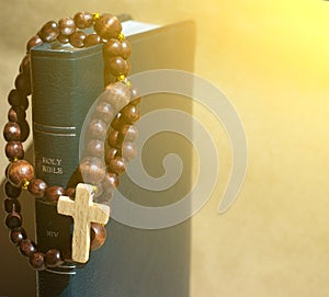 spiritual background with Wooden rosary on the Bible in the aureole of the divine of Divine Rays and place for inscription