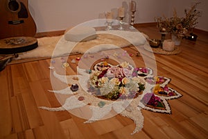 spiritual ceremony with flowers and rice in the shape of a moon, sun, fire and star on a wooden floor, shaman
