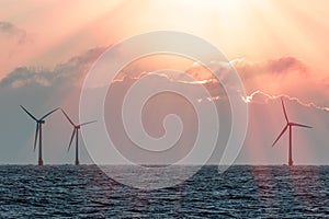 Spiritual global warming image of wind turbines under emerging sunlight