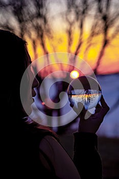 Spiritual Indian Woman seeing and watching a Crystal Lens Ball during a Colorful Sunset