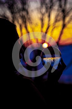 Spiritual Indian Woman seeing and watching a Crystal Lens Ball during a Colorful Sunset