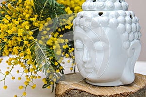 Spiritual ritual meditation face of Buddha on wood, home decor, mimosa yellow spring flowers