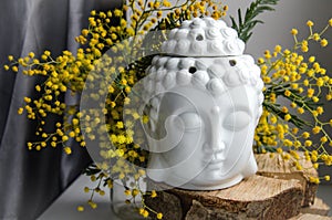 Spiritual ritual meditation face of Buddha on wood, home decor, mimosa yellow spring flowers