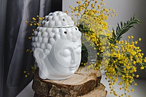 Spiritual ritual meditation face of Buddha on wood, home decor, mimosa yellow spring flowers